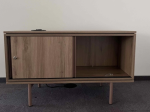 Używana szafka RTV na nóżkach w kolorze drewna z przesuwnymi drzwiami