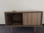 Używana szafka RTV na nóżkach w kolorze drewna z przesuwnymi drzwiami